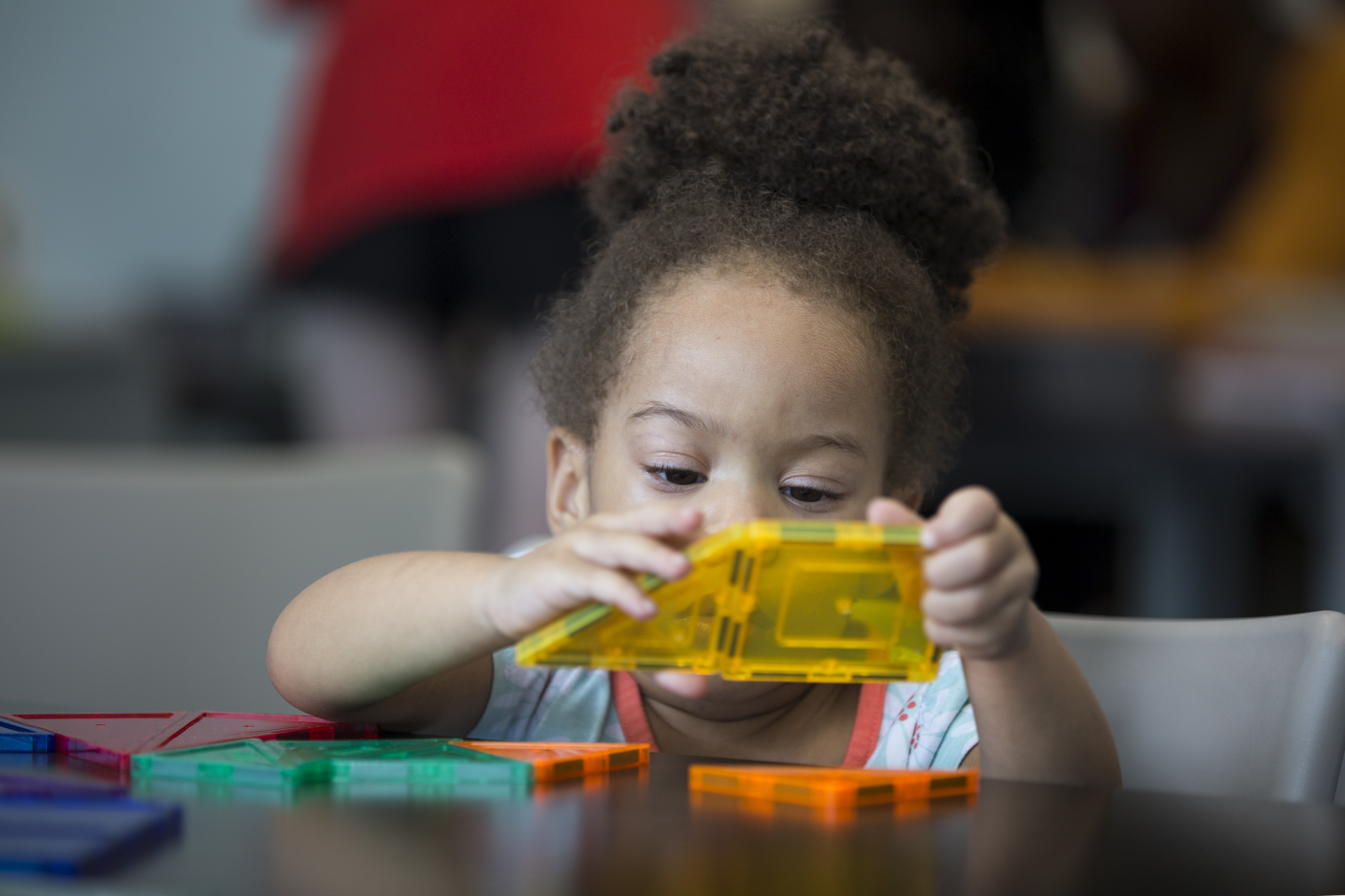 A preschool aged Black girl plays with multicolored blocks on a table at Richland Library Blythewood